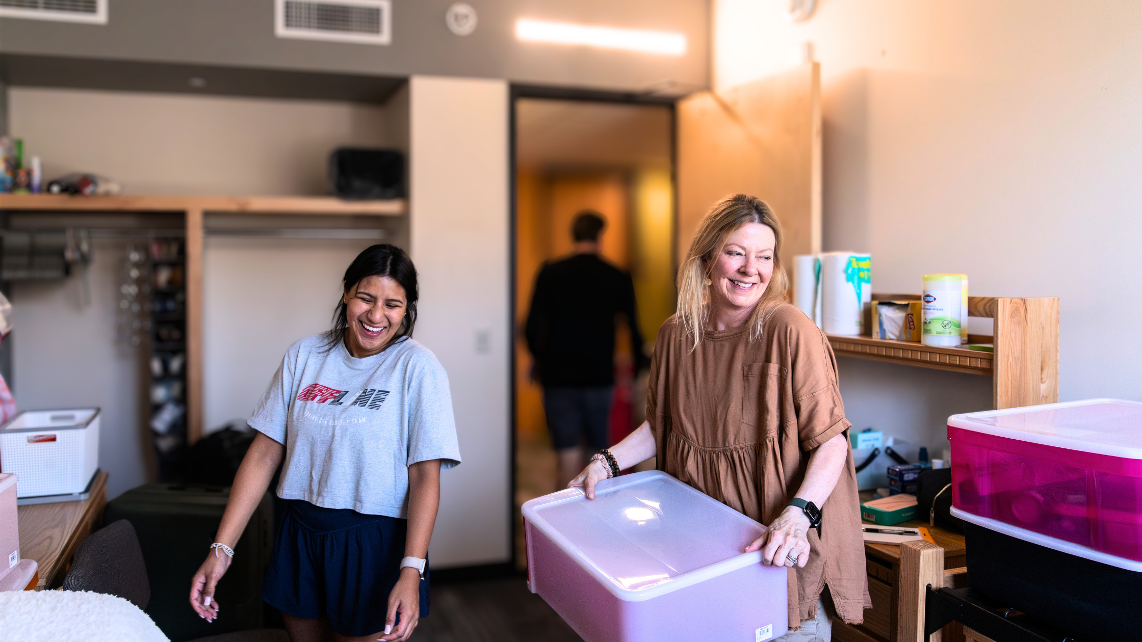 2 people in the dorms smiling and unpacking